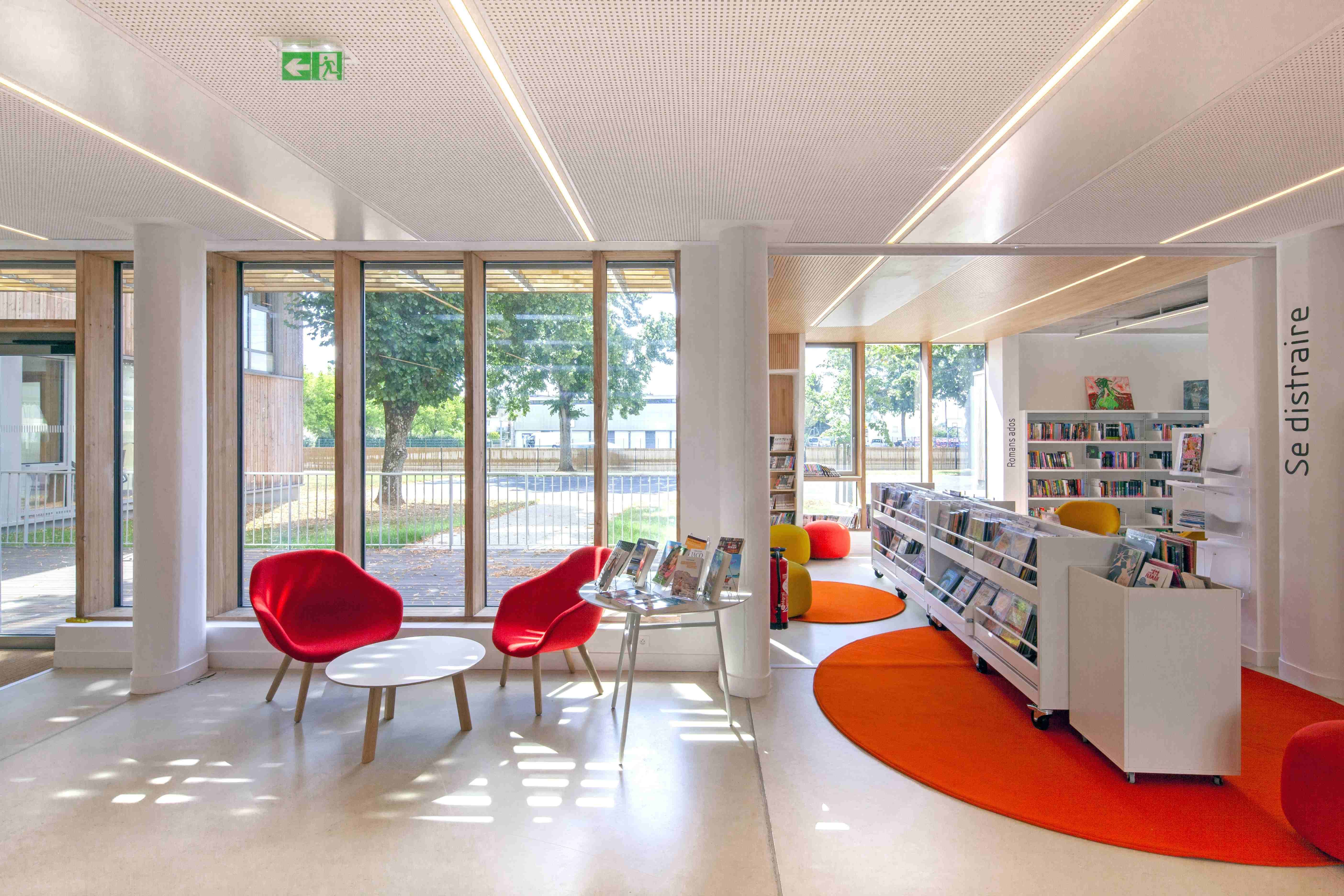 intérieur de la médiathèque de Courteille comprenant des sièges, des baies vitrées et des étagères de bande dessinées